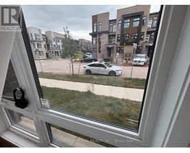 A view from a window looking out at a parking lot with cars and a building in the distance.