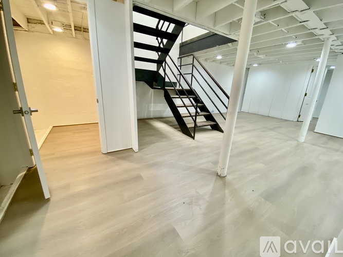 A spacious room with a staircase and wooden flooring.
