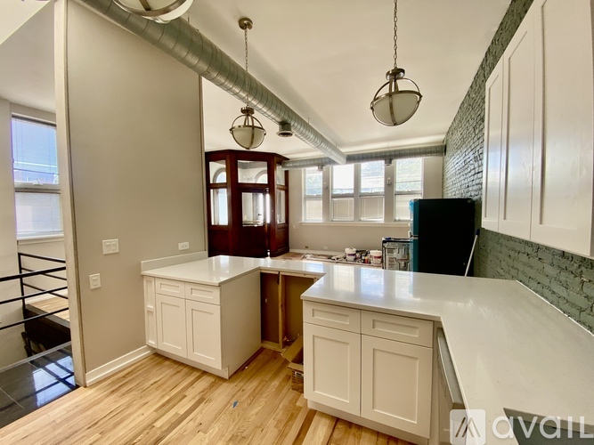 A kitchen with white cabinets and a wooden floor.