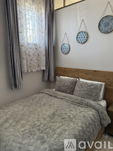 A bedroom with a bed, pillows, and decorative hanging plates on the wall.