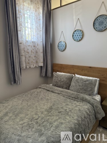 A bedroom with a bed, pillows, and decorative hanging plates on the wall.