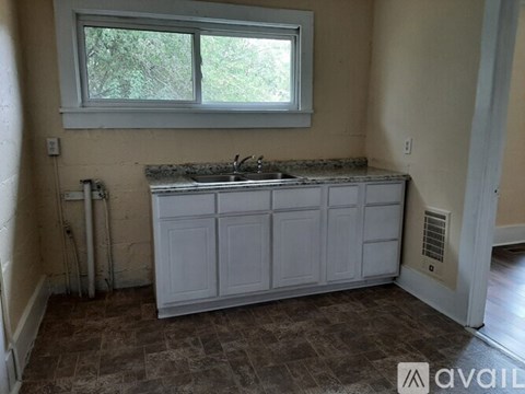 A kitchen with a window, sink, and cabinets.