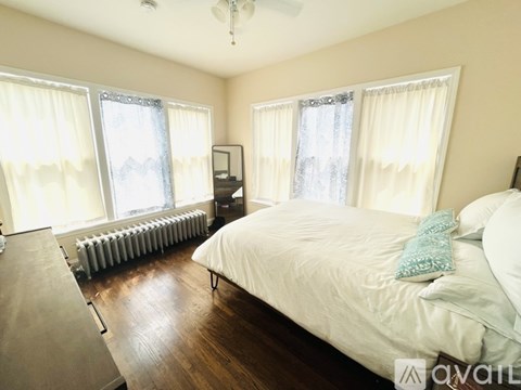 A bedroom with a large bed and a window with curtains.