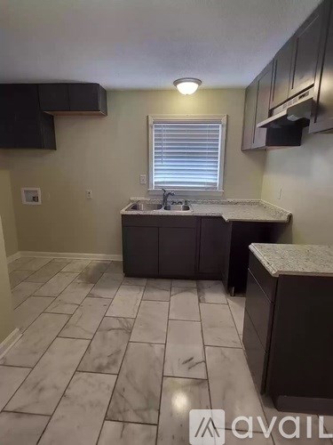 A kitchen with a marble tile floor and dark cabinets.