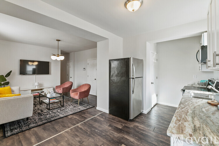 A kitchen with a black fridge and a dining table with chairs.