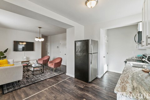 A kitchen with a black fridge and a dining table with chairs.