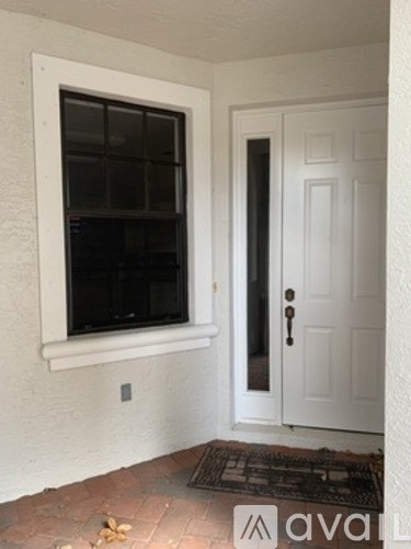 A white door with a black handle is next to a window.