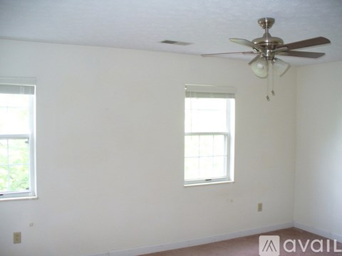 A room with a ceiling fan and two windows.