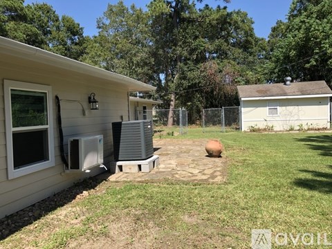 A house with a white wall and a window is surrounded by a fence.