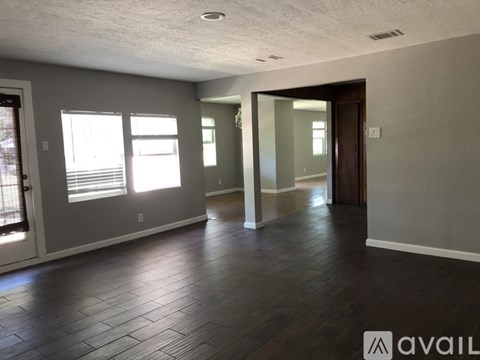 A spacious room with wooden flooring and a sliding glass door.