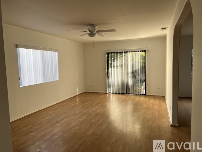 A spacious room with wooden flooring and a ceiling fan.