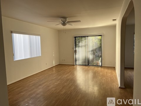 A spacious room with wooden flooring and a ceiling fan.