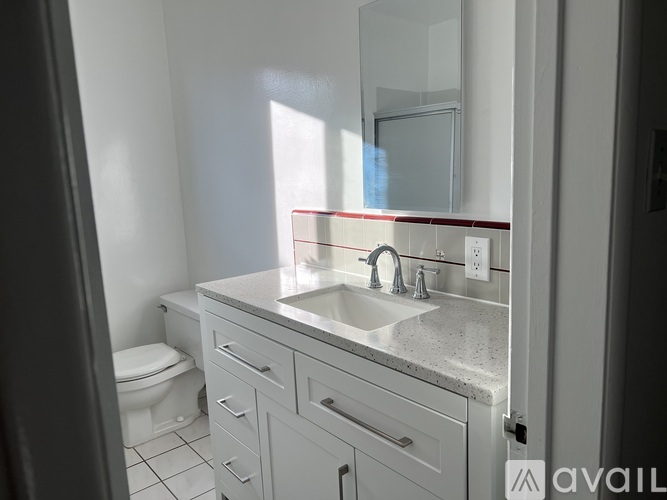 A bathroom with a toilet, sink, and mirror.