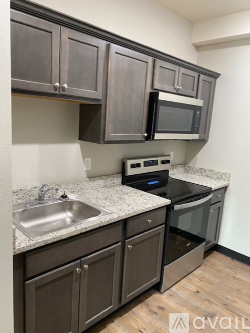 A kitchen with dark brown cabinets and a granite countertop.