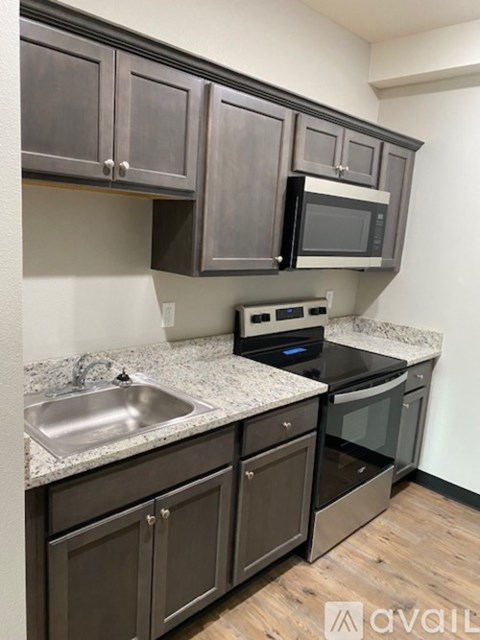 A kitchen with dark brown cabinets and a granite countertop.