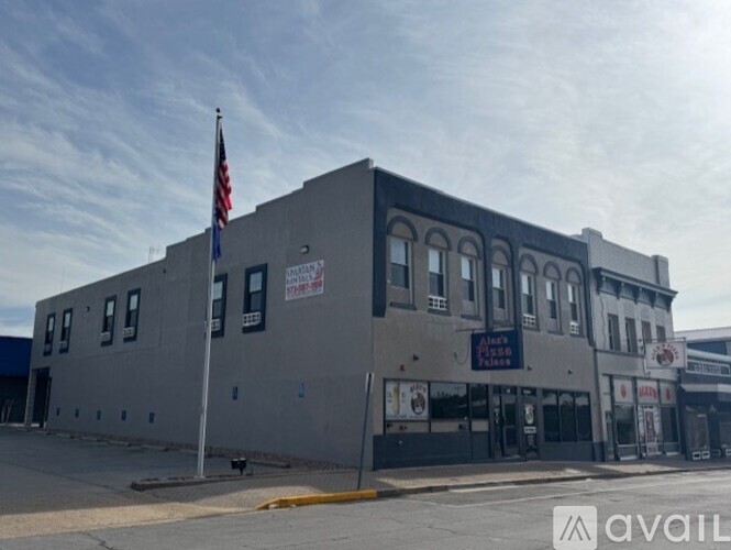 A grey building with a flag on top and a sign that says "AVAILABLE".