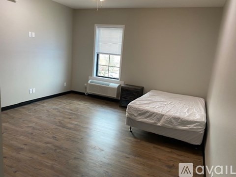 A bedroom with a bed, a window with blinds, and a radiator on the window.