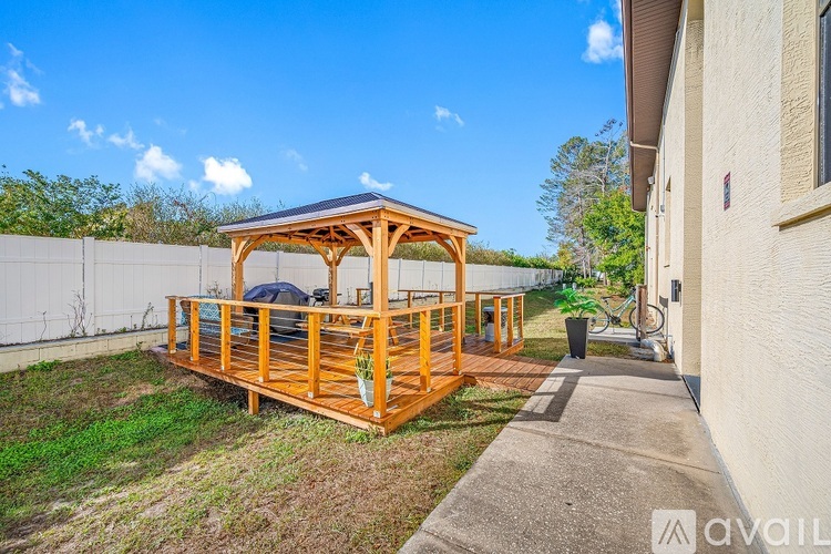 A wooden gazebo with a blue roof is situated in a backyard.