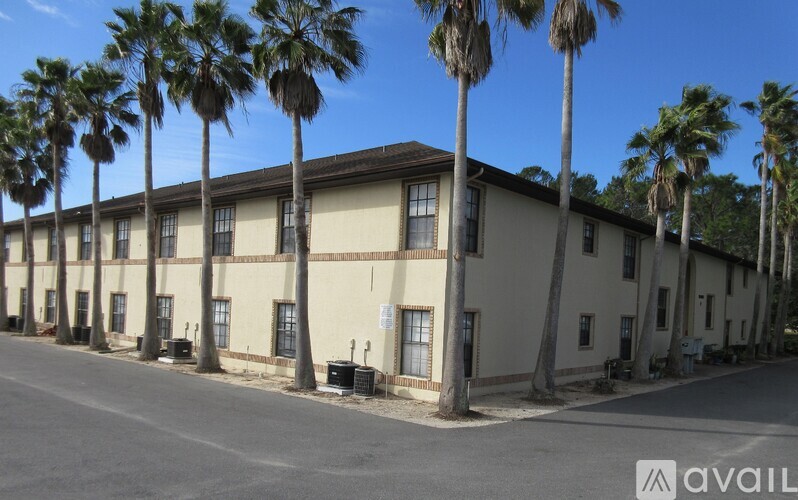 A row of palm trees in front of a building.