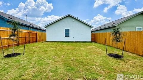 A backyard with a blue house, a white house, and a wooden fence.