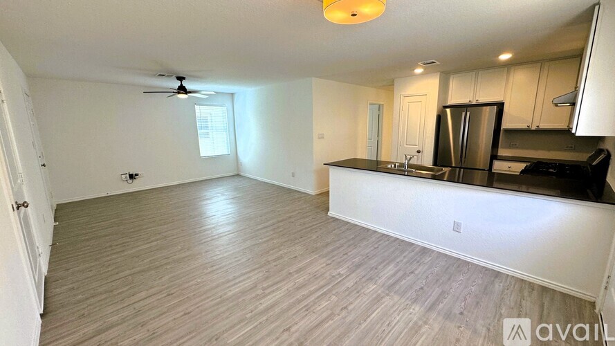A spacious kitchen and living room with hardwood floors and white walls.