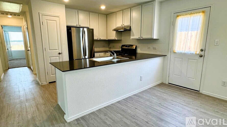 A kitchen with white cabinets and a black countertop.