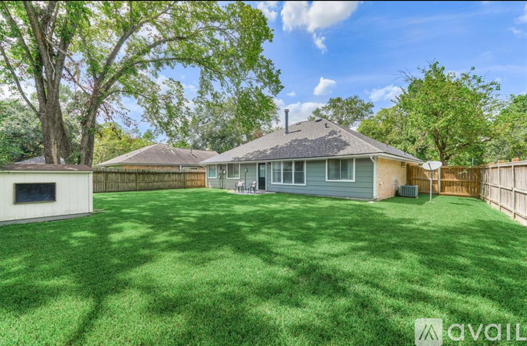 A house with a large lawn and trees in the background.