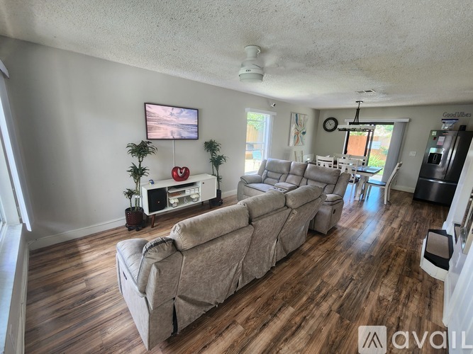 A living room with a large couch and a flat screen TV mounted on the wall.