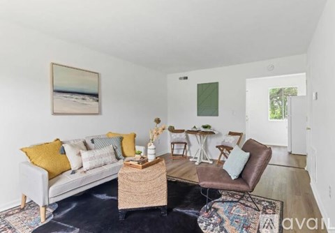 A living room with a white couch, a brown chair, and a painting on the wall.