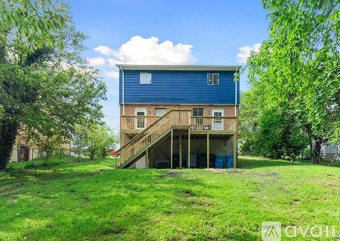 A blue house with a deck and a garage is surrounded by greenery.