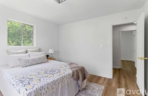 A bedroom with a bed, lamp, and window.