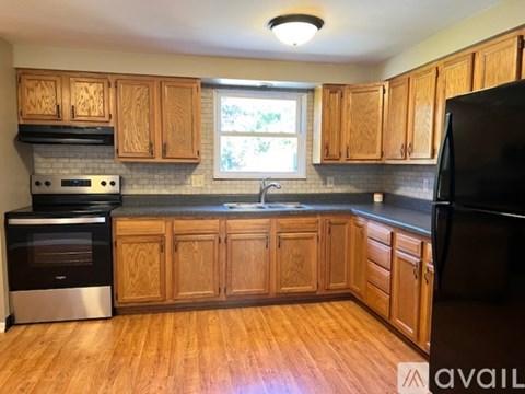A kitchen with wooden cabinets and a black refrigerator.