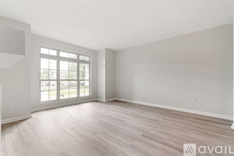 A spacious room with a large window and wooden flooring.