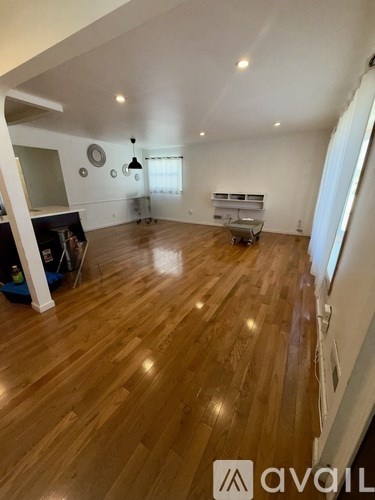 A spacious room with wooden flooring and a white ceiling.