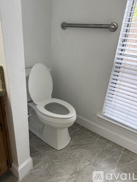 A white toilet in a bathroom with a towel rack above it.