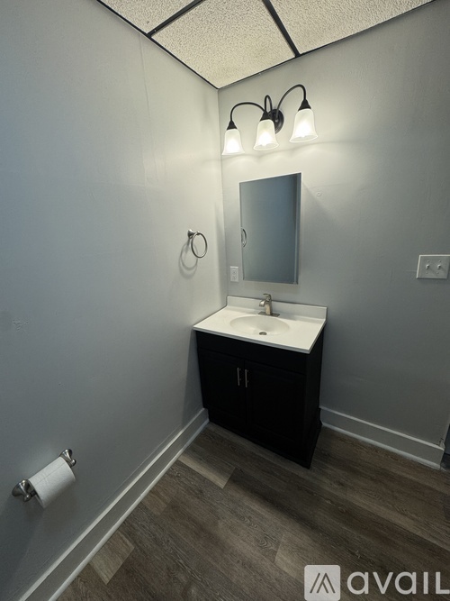 A bathroom with a sink, mirror, and light fixture.