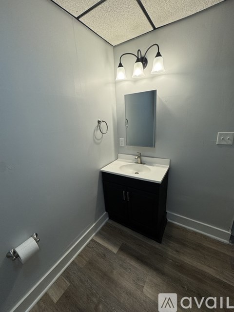 A bathroom with a sink, mirror, and light fixture.