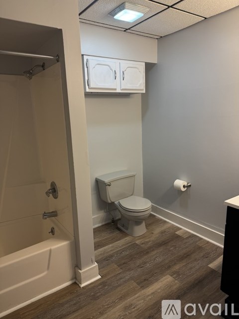 A bathroom with a toilet, a bathtub, and a cabinet above the toilet.