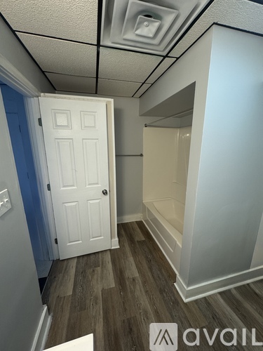 A room with a white door and a wooden floor.