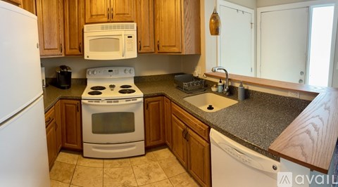 A kitchen with a white stove top oven and a white dishwasher.