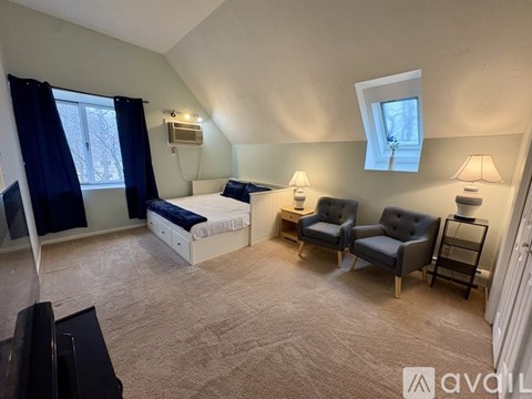 A bedroom with a bed, two chairs, and a television.