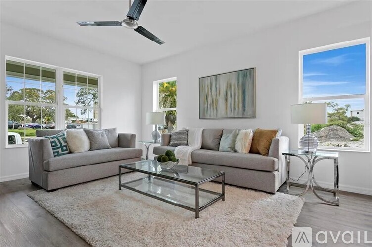 A living room with a grey sofa, a glass coffee table, and a painting on the wall.