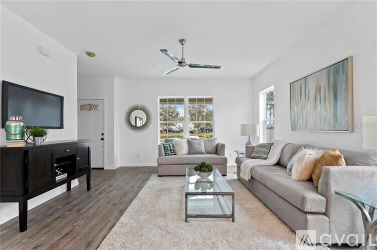 A living room with a grey couch, a glass coffee table, and a television on a cabinet.