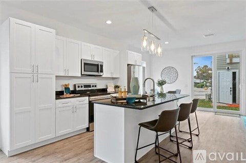 A modern kitchen with white cabinets and a black countertop.