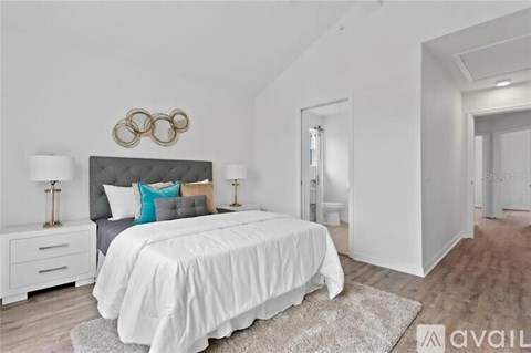 A bedroom with a large bed, a nightstand with two lamps, and a wall decoration above the bed.
