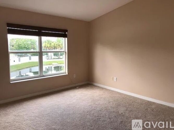 A room with a carpeted floor and a window overlooking a parking lot.