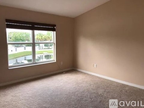 A room with a carpeted floor and a window overlooking a parking lot.