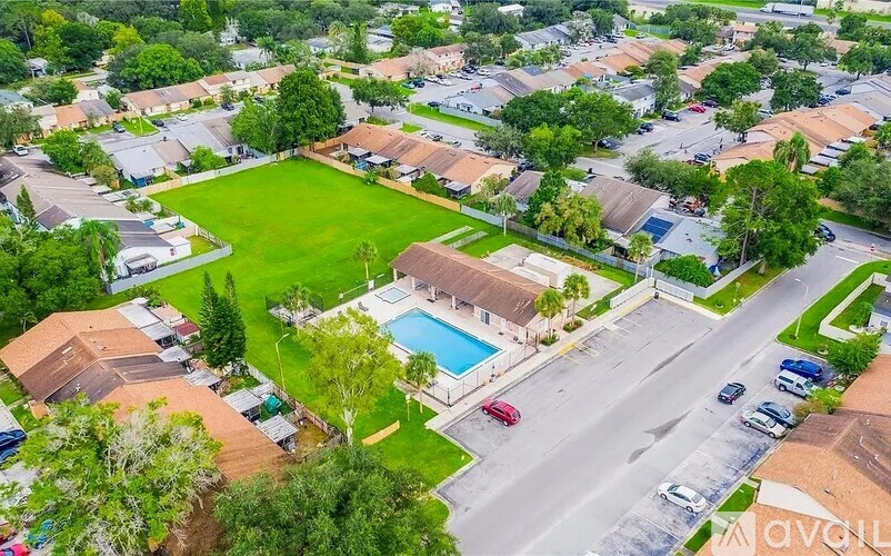 A bird's eye view of a residential area with houses, a pool, and a road.