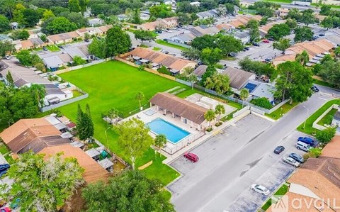 A bird's eye view of a residential area with houses, a pool, and a road.