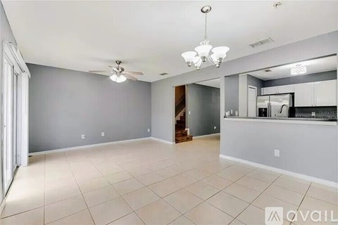 A spacious room with a ceiling fan and a chandelier.